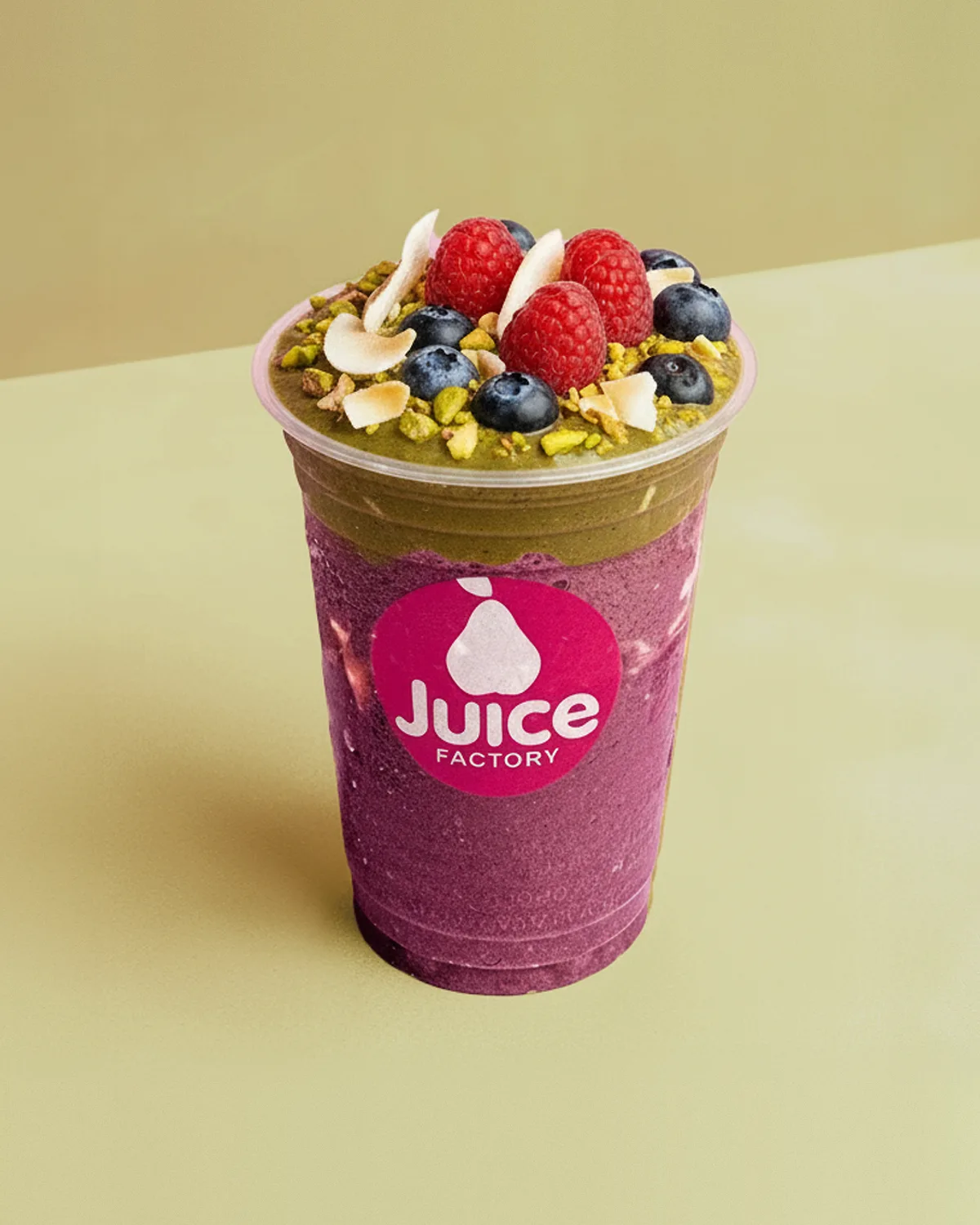 Açaí Pistachio im Becher vor olivgrünem Hintergrund