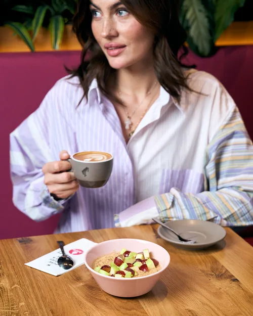 Woman on the pink bench at Juice Factory with a caffè latte