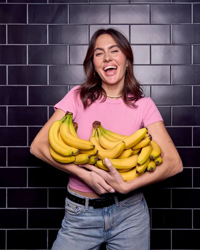 A woman laughing with an armful of bananas
