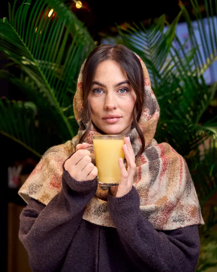 Woman in a scarf holding a fresh ginger tea