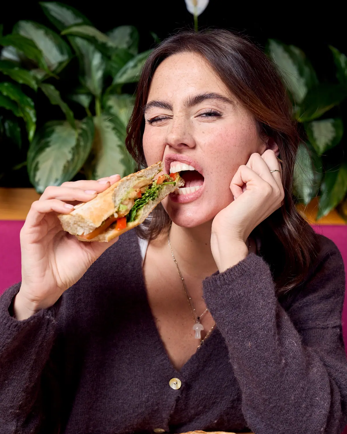 Woman laughing as she bites into a toasted sandwich