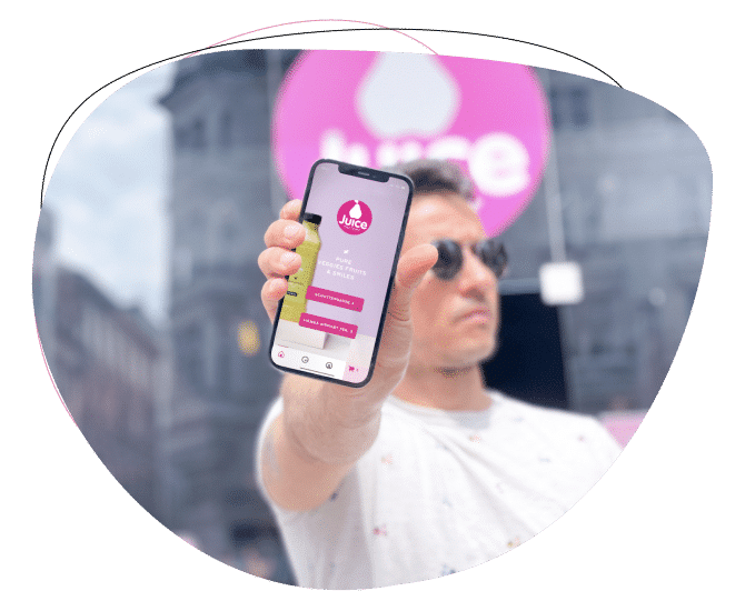 Eine Person mit Sonnenbrille hält ein Smartphone mit der Juice-App hoch. Der Hintergrund ist unscharf, hinter der Person ist ein großes, rundes, rosa Juice-Logo zu sehen.