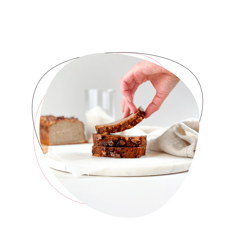 Hand nimmt Bananenbrotstück von Teller.