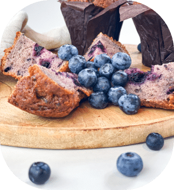 Blaubeer-Muffins und frische Blaubeeren auf Holzbrett