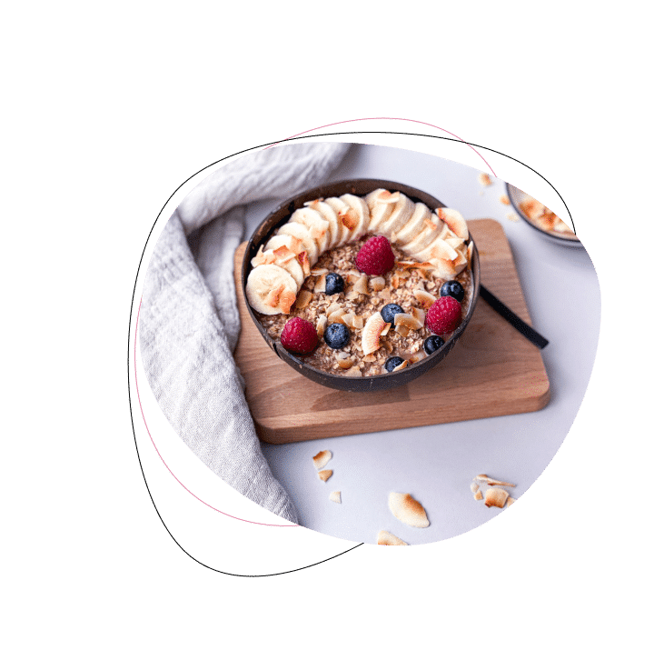 Gesundes Müsli mit Bananen, Beeren und Nüssen auf Holzbrett.